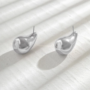 Macro shot of silver-toned metal teardrop earrings with a polished mirror finish