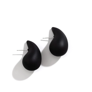Close-up of matte black teardrop earrings with fluid geometric design on white background