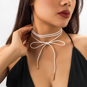 Detailansicht eines weißen Samt-Chokers mit Schleifen-Design und goldenen Endkappen
