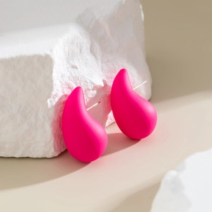 Macro detail of large rose red teardrop earrings with smooth matte finish on a stone base