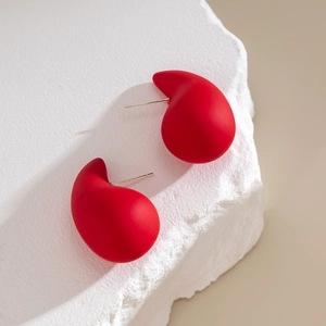 Close-up of matte red teardrop earrings with S925 silver hallmarks on white stone