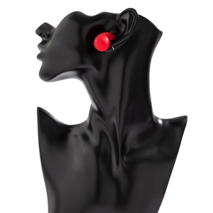 Macro detail of glossy red crescent drop earrings on a sleek black art mannequin model