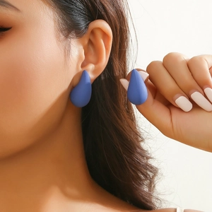 Deep blue matte teardrop stud earrings shown on model ear for size and texture detail