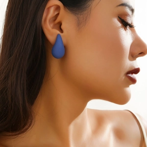 Close-up of minimalist matte dark blue teardrop earrings worn by a female model