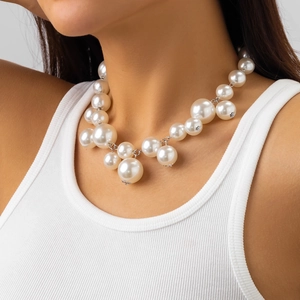 Close-up van grove parelchoker met zilveren metalen sterren gedragen door model