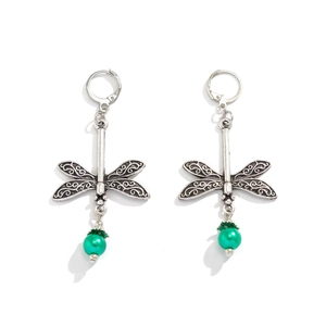 Close-up of vintage silver dragonfly earrings with hollow carving and green beads
