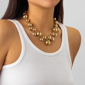Detail van een dikke gouden kralenketting met grote gepolijste bollen bij een model