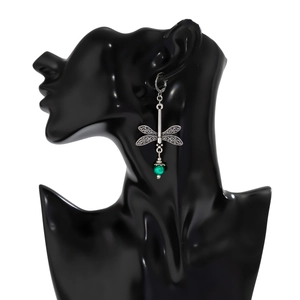 Detailed view of vintage silver dragonfly earrings with hollow wings and green bead drop