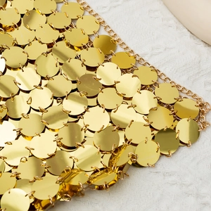 Detail von goldenen Metallpailletten-Netz mit feiner Kette auf weißem Strukturstoff