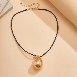 Detail of polished gold teardrop pendant with black cord and adjustable lobster clasp