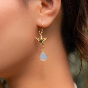 Macro view of vintage gold bird earrings with water drop opal stone on a model