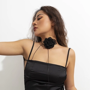 Detail of a black fabric flower choker with long adjustable straps on a model
