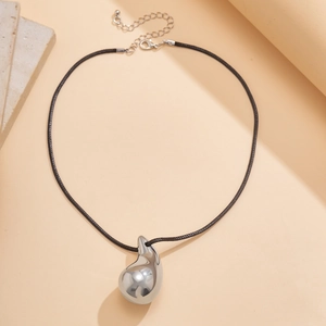 Macro shot of large polished silver teardrop pendant on minimalist black cord necklace