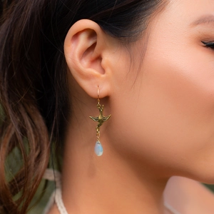 Detail of vintage bronze swallow earring with blue opal bead on model ear