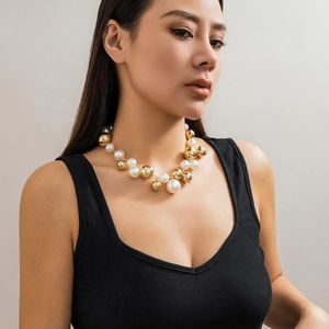 Detail van grote witte imitatieparels en gepolijste gouden metalen kralen op choker