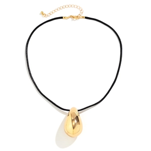 Close-up of a large polished gold teardrop pendant with adjustable black cord necklace