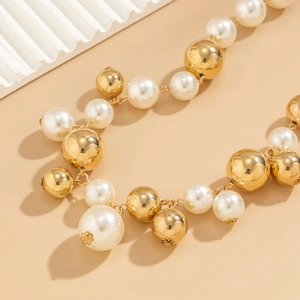 Macro-detail van grote witte parels en gepolijste gouden metalen kralen op choker