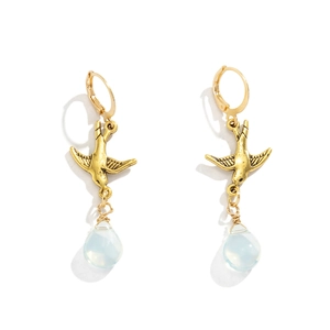 Detail of vintage gold swallow earrings with translucent water drop pendants on white background