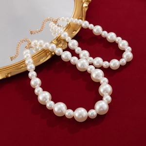 Macro detail of multi-layered pearl choker necklace with gold clasp on red velvet