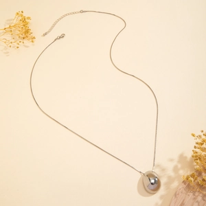 Macro shot of silver teardrop pendant necklace with polished mirror finish and lobster clasp
