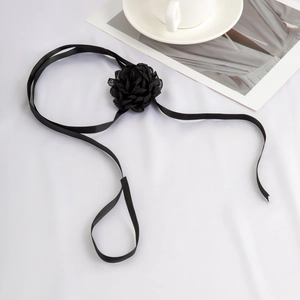Detail of elegant black fabric flower choker with adjustable satin ribbon on white surface
