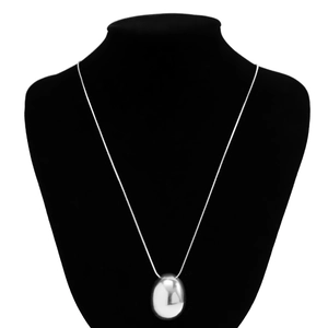 Macro detail of high-polish silver teardrop pendant on a sleek snake chain necklace