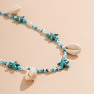 Détail de la chaîne de corps avec étoiles turquoise, coquillages et perles