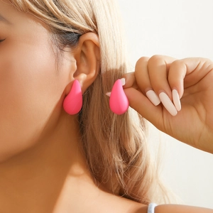Hot pink teardrop stud earrings with a matte finish shown on a model for a punk style