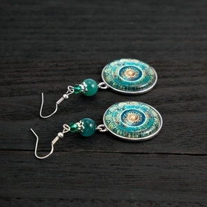 Detail of bohemian mandala drop earrings with turquoise beads on dark wood background