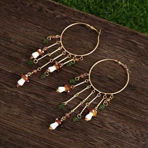 Détail de boucles d'oreilles créoles boho avec pendentifs champignons et pampilles