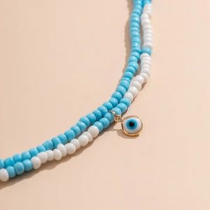 Détail de chaîne de corps en perles turquoise avec un pendentif œil protecteur doré