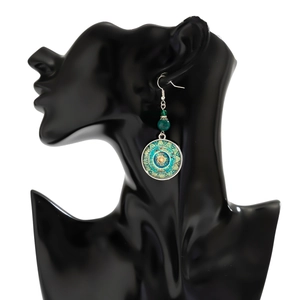 Detail of bohemian mandala earrings with teal stone on a black model silhouette