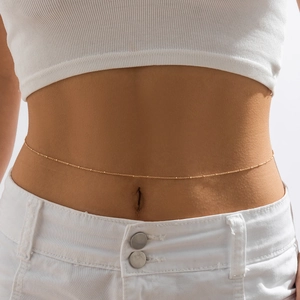 Detail of a thin gold beaded body chain worn on the waist for a sexy beach fashion look