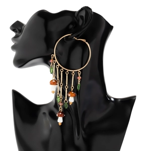 Detail of large gold hoops with mushroom and leaf charms on a black display model