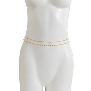 Détail d'une chaîne de taille dorée à double rangée avec perles blanches sur un mannequin