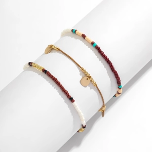 Nahaufnahme von dreiteiligen Boho-Perlenarmbändern mit goldenen Scheibenanhängern