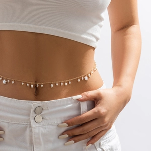 Detail of gold chain waist belt featuring white pearls and star pendants on a white dress