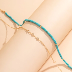 Détail de la chaîne de corps bohème en perles turquoise et chaîne dorée avec coquillage