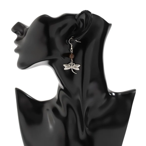 Close-up of vintage dragonfly drop earring with a brown bead on a black display stand