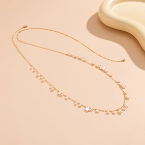Detail of gold chain body jewelry featuring white pearls and star pendants on soft background