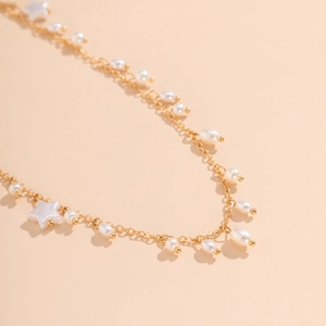 Detailed macro view of the gold-plated chain featuring white pearls and star pendant