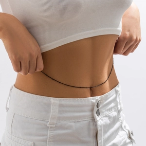 Detail of minimalist black metal bead waist chain on model wearing white crop top