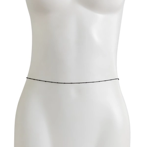 Macro detail of minimalist black beaded waist chain layered on white mannequin body