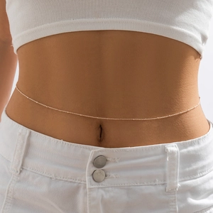 Close-up of minimalist gold thin waist chain on model wearing white crop top