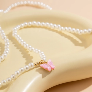 Detail of a pearl body chain featuring a pink butterfly pendant with gold metal edges