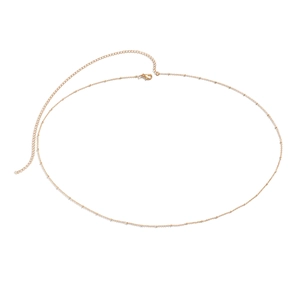 Detail of a minimalist gold bead waist chain with lobster clasp and adjustable links