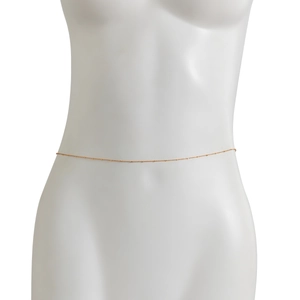 Detail of a slender gold metal waist chain on a mannequin for beach vacation styling