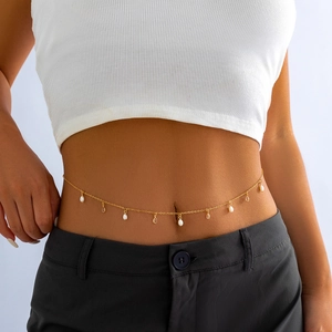 Detail of gold metal body chain with white pearls and teardrop pendants on female model