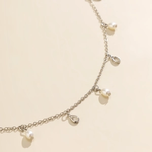 Macro view of silver chain detail with teardrop pearls and clear crystal pendants