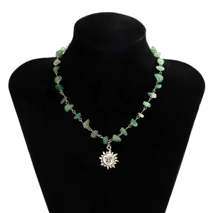 Detailed close-up of a vintage sun pendant on a necklace made of irregular green stones